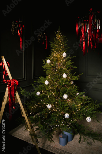 Obraz na płótnie Beautiful New Year decor, a Christmas tree with a golden staircase in the stylish dark interior of the living room w salonie