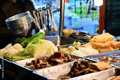 At a stall in Nanjichang Night Market, this close-up shows various vegetables like cabbage, green peppers, and string beans, along with enoki mushrooms. Various ingredients include tofu and vermicelli photo