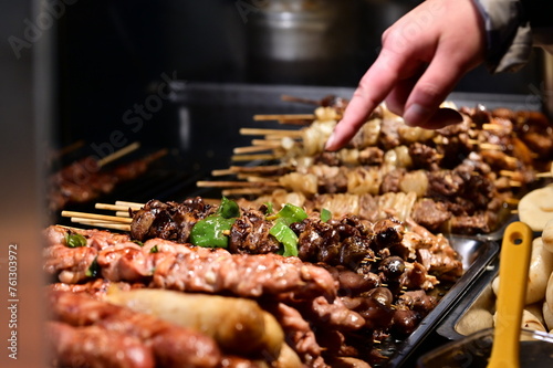 In Nanjichang Night Market, a spot known for its affordable and diverse food, this close-up showcases various skewered ingredients at a barbecue stall. It includes chicken, wild boar, bell peppers.