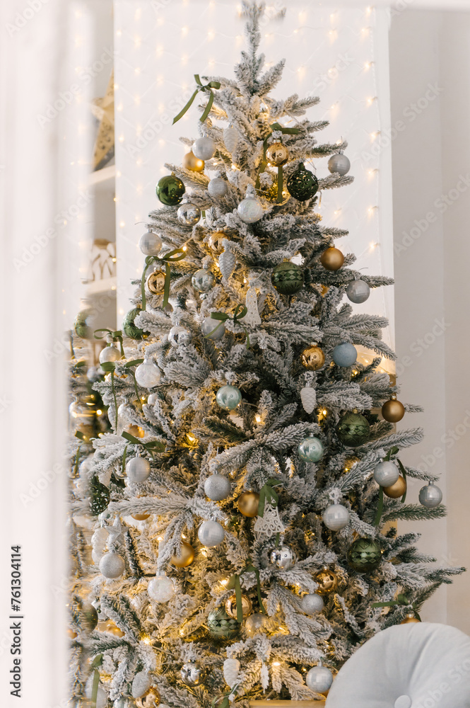 Christmas decor, beautiful snow-covered Christmas tree with toys and lights