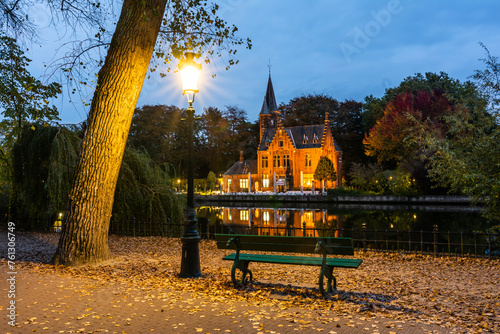 A romantic spot after the sunset with bench and street lamp by the lake Minnewater in park in Bruges in the early autumn with the view towards the Castle de la Faille photo