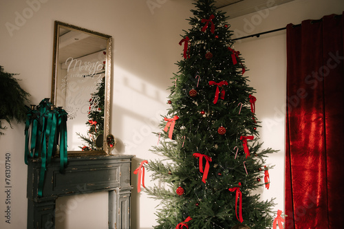 Obraz na płótnie Beautiful New Year decor, the Christmas tree is decorated with red bows in the stylish interior of the living room w salonie