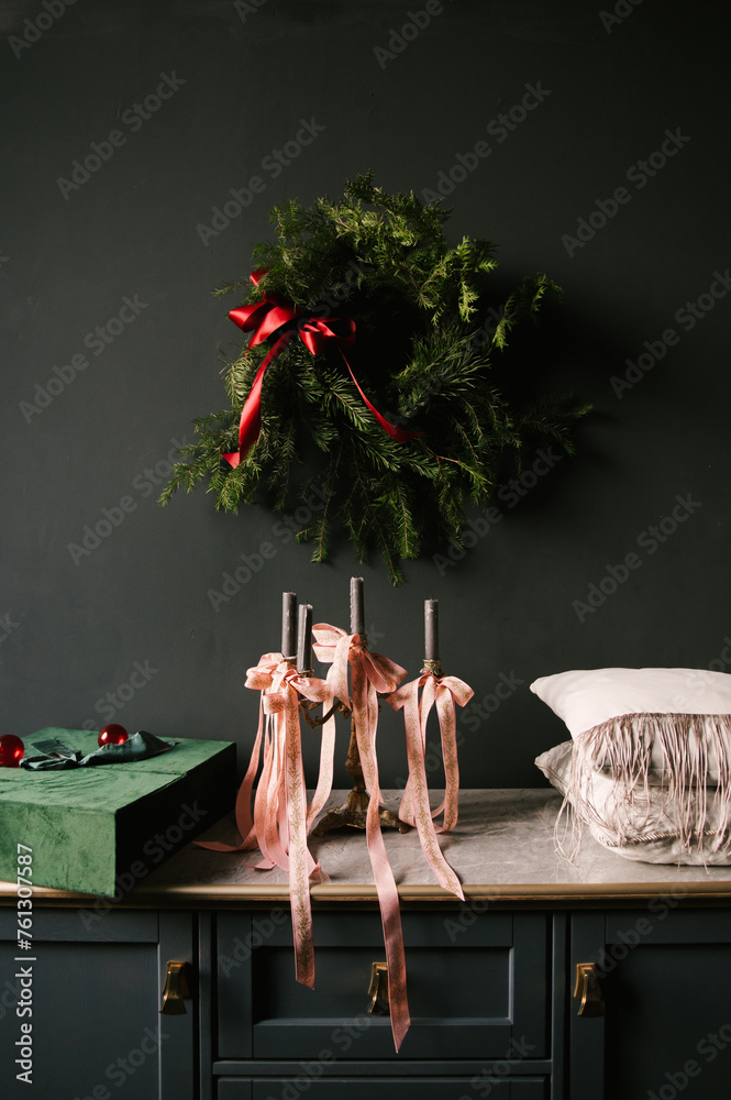 Beautiful New Year decor, a Christmas wreath on a vintage chest of drawers in a stylish dark living room interior