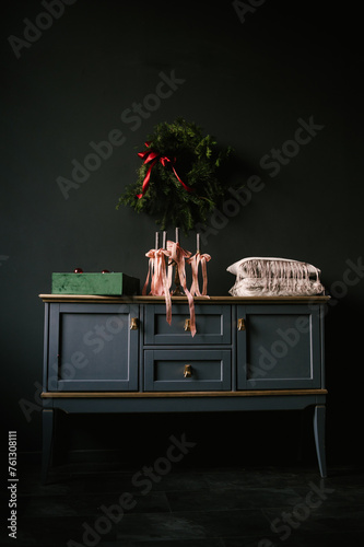 Obraz na płótnie Beautiful New Year decor, a Christmas wreath on a vintage chest of drawers in a stylish dark living room interior w salonie
