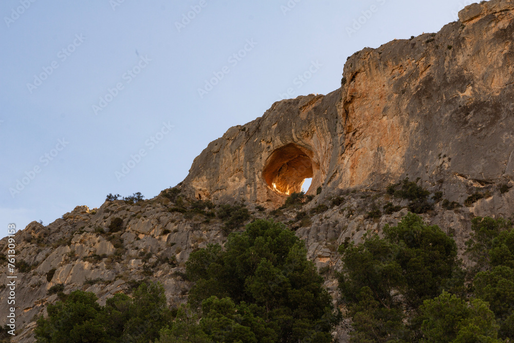 Top of a mountain with a through cave, and trees at the foot. Spain, Alicante. Busot
