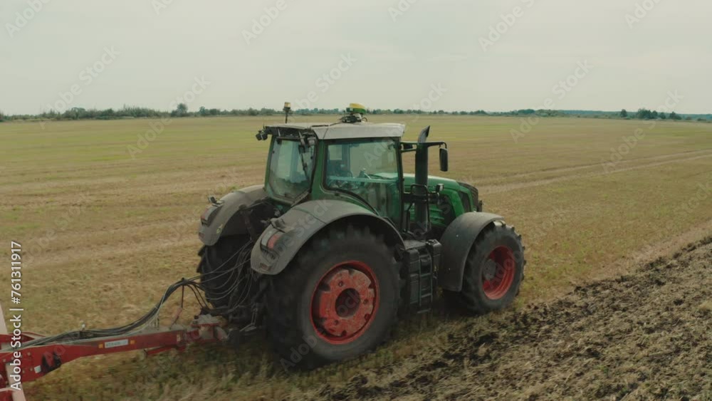A tractor in an agricultural field while working with a plow. Smooth shots of a tractor from a drone at low altitude. A tractor in an agricultural field while working with a plow. Smooth shots of a tractor from a drone at low altitude.