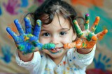Cheerful child with hands painted in vivid colors against a colorful artwork background