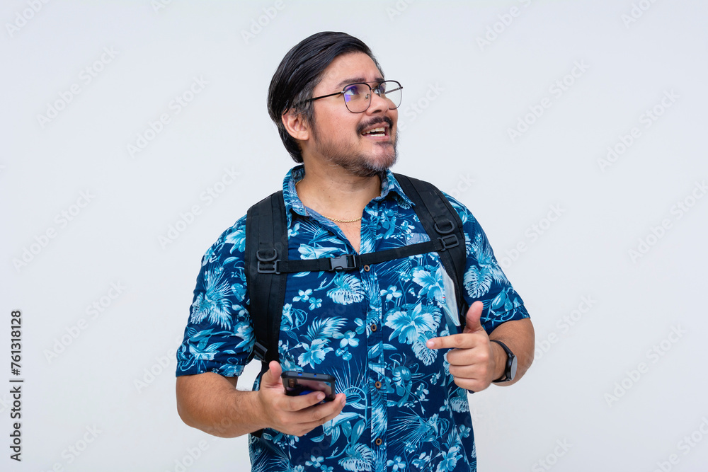 Perplexed male traveler in a floral shirt with glasses looking lost seeking navigation aid on his phone against a white backdrop. Perplexed male traveler in a floral shirt with glasses looking lost seeking navigation aid on his phone against a white backdrop.