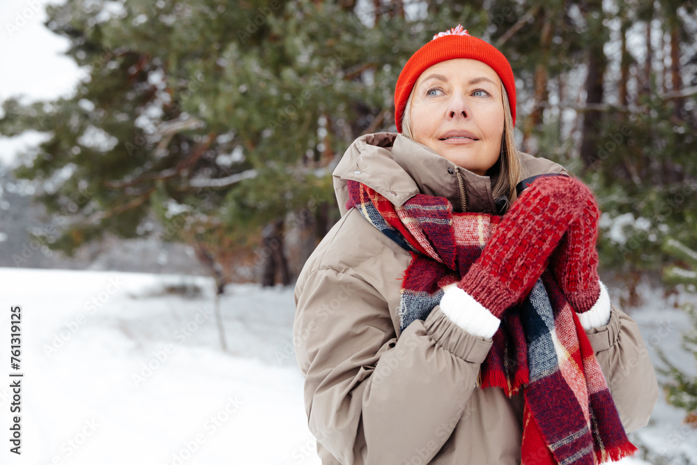 Obraz premium Smiling mature woman in red hat having hot tea outdoors