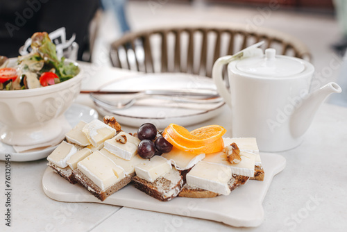 Brie cheese with dark bread snack decorated with grapes, orange and walnuts. 