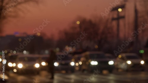 Climate Change. Global Warming. Fossil Fuels. Blurred Cars Wait at the Traffic Lights on the Road Intersection in the Evening While Cars from the Side Drive by and Pedestrians Walk Across, Sarajevo photo