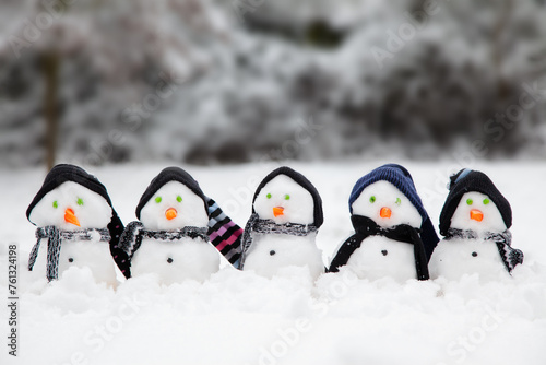 Cute little snowmen dressed in hats and scarfs in snow