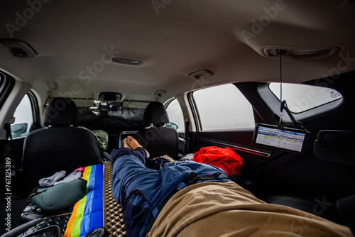 View from the inside of a camperized vehicle with the legs of a young man on the bed