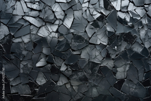 A complex mosaic of broken black glass pieces creates a textured abstract surface.
