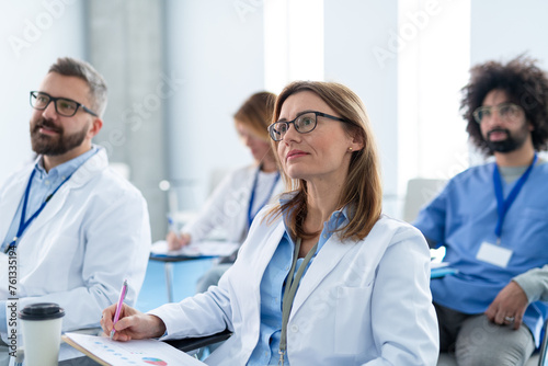 Group of doctors on conference, medical team sitting and listening speaker. Medical experts attending an education event, seminar in board room. photo