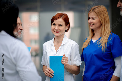 Team of doctors discussing surgery success, walking across corridor. Colleagues, doctors team discussing patients diagnosis.