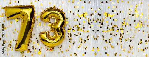 Golden foil balloon number, figure seventy-three on white with confetti background. 73th birthday card. Anniversary concept. birthday celebration