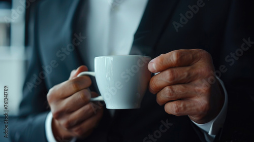 Man in suit holding white coffee cup