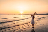 Young woman traveler relaxing and enjoying the beautiful sunset on the tranquil beach, Travel on the summer vacation concept