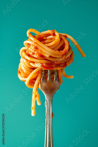 Italian spaghetti twirled around on a fork with meaty bolognaise sauce, isolated against a graduated teal background with copyspace.