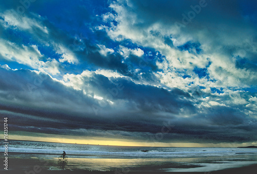 Bicycle rider on the beach at Rincon California before a winter storm photo