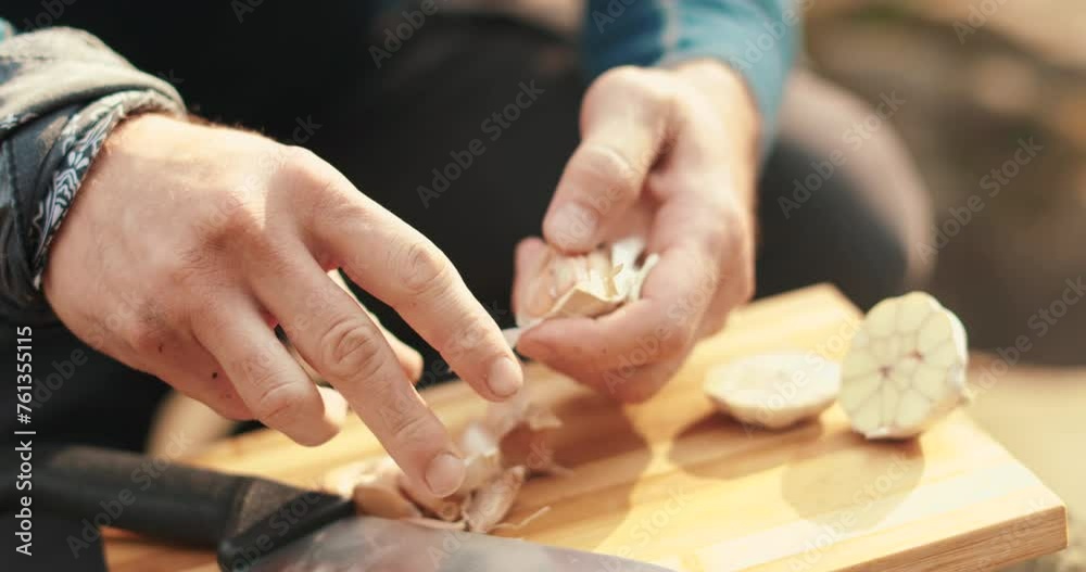 A man peels fresh garlic with his hands. Preparation for cooking. Outdoor cooking. A man peels fresh garlic with his hands. Preparation for cooking. Outdoor cooking.
