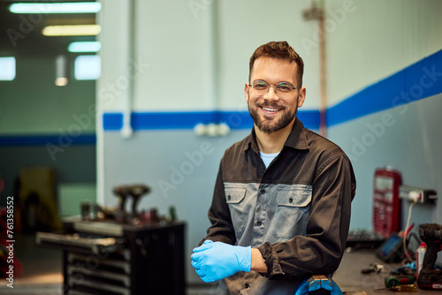 A smiling mechanic technician working at his car repair service, posing for the camera. photo
