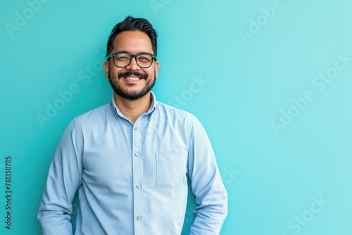 Man with glasses is smiling and wearing blue shirt