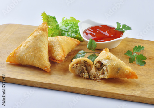 Chicken Samosa with ketchup and one samosa is broken to show samosa filling