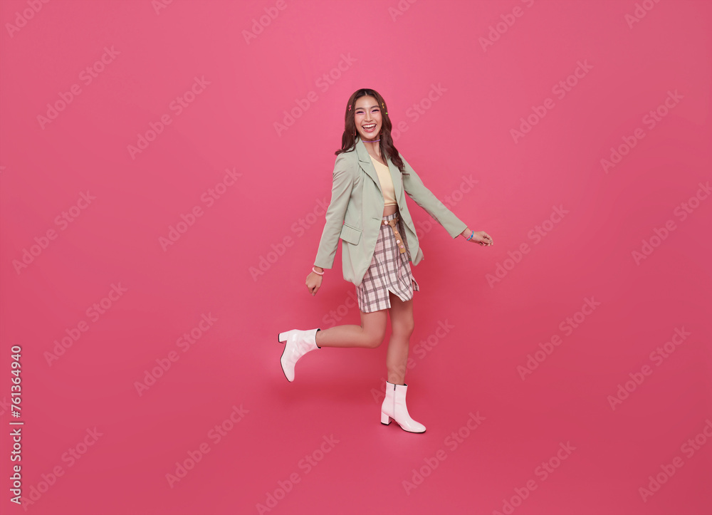 Full body smiling happy young Asian teen woman walking going strolling and looking sideways isolated on pink background studio portrait. Full body smiling happy young Asian teen woman walking going strolling and looking sideways isolated on pink background studio portrait.