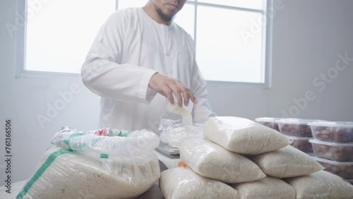 Muslim Man Pouring Rice Grain Into Plastic Bags, Packing for Food Donation on Ramadan. Islamic Charity Concept photo