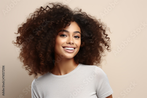 Woman with curly hair is smiling and wearing white shirt