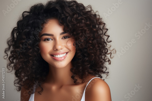 Woman with curly hair is smiling and looking at camera