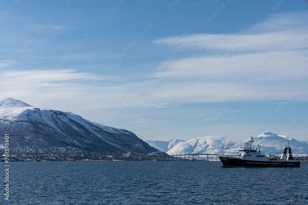 Fishing vessel and Tromsø Bridge with winter mountain landscape, Tromso, Norway