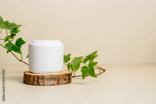 Care facial cream mockup container on wooden podium with green leaves, copy space. Mockup cream bottle for beauty products. Natural organic skincare, body lotion, face cream