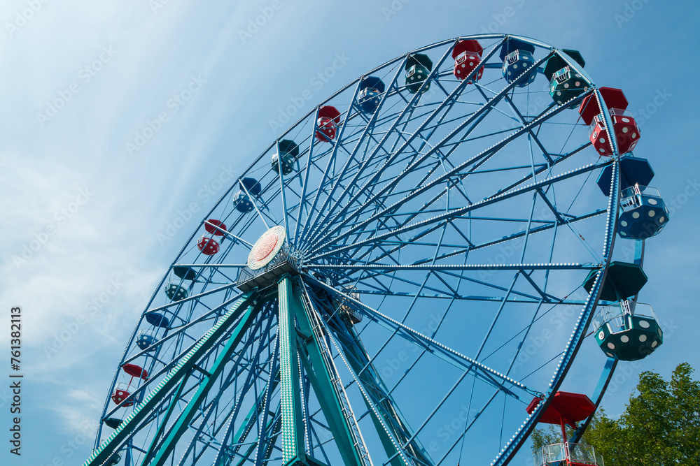 Colorful ride ferris wheel in motion in amusement park on sky background.