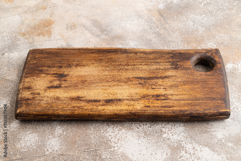 Fototapeta premium Empty rectangular wooden cutting board on brown concrete. Side view
