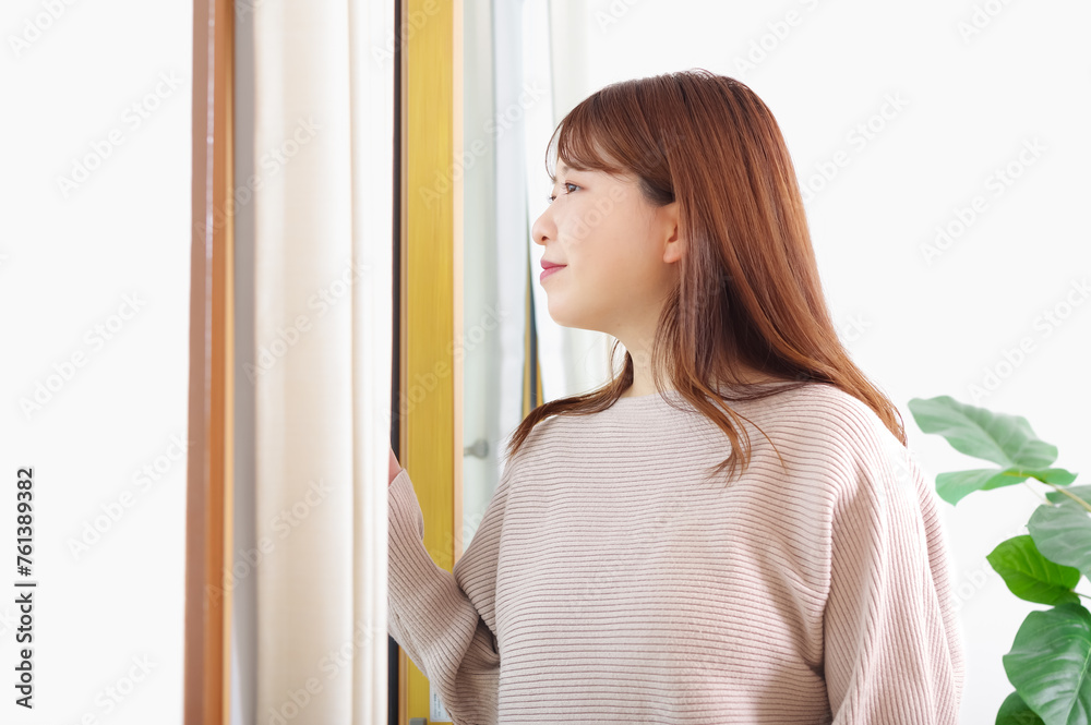 明るい窓際に立つ若い女性