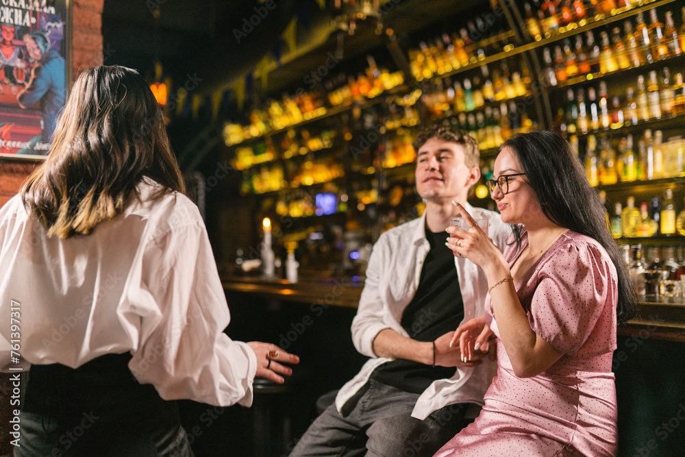 Relax and spiritual atmosphere after hard day at club. Young people spend time together with alcoholic cocktails in cozy bar