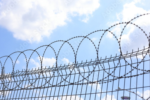 stainless steel razor wire fence. barbed wire against blue sky