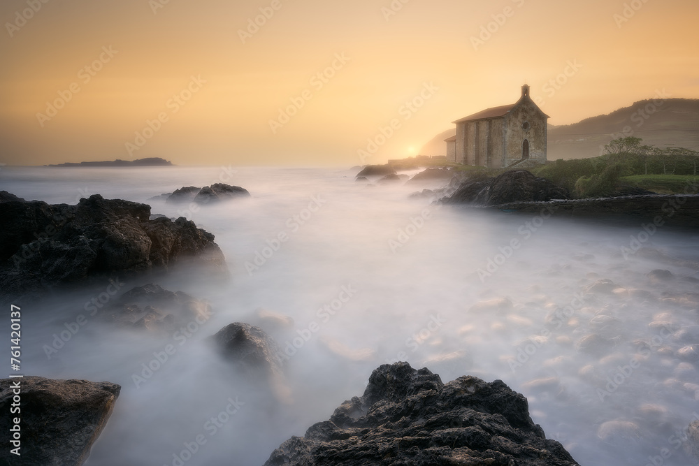 calm waves in the Cantabrian Sea in a warm dawn in front of the hermitage of Santa Katalina in Mundaka