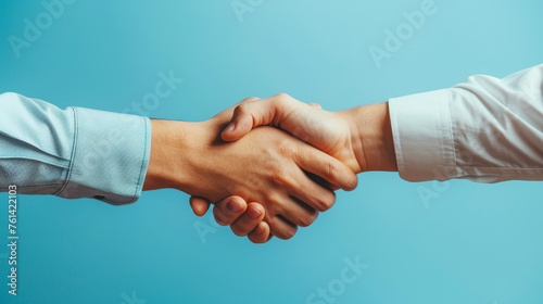 Business handshake against a blue background representing partnership and agreement