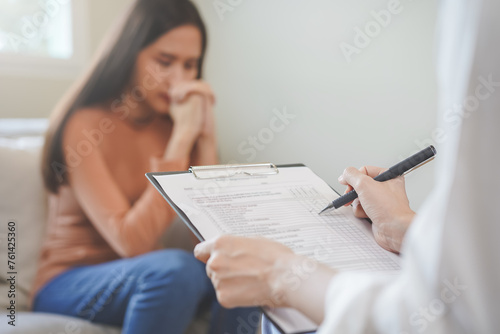 Psychology, depression. Sad, suffering asian young woman, girl consulting with psychologist, psychiatrist while patient counseling mental with doctor hand taking notes at clinic. Encouraging, therapy. photo
