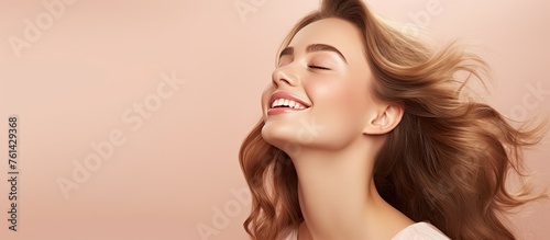 A womans eyes are closed in a joyful smile, her hair is being tousled by the wind, giving her a carefree and happy look