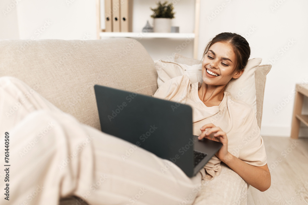 Smiling Woman Freelancing at Home with Laptop in Modern Domestic Setting Smiling Woman Freelancing at Home with Laptop in Modern Domestic Setting