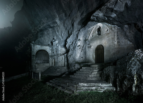 Cover of the hermitage carved into the rock of San Bernabe in Ojo Guareña, illuminated on a cold foggy night photo