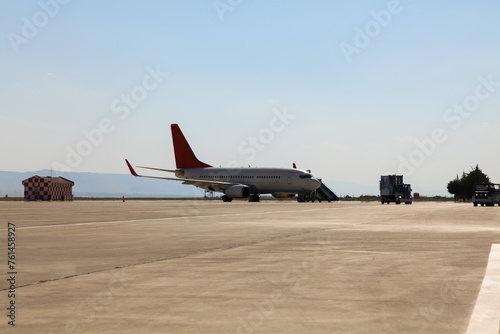 Airport view with commercial airplane, apron and runway.