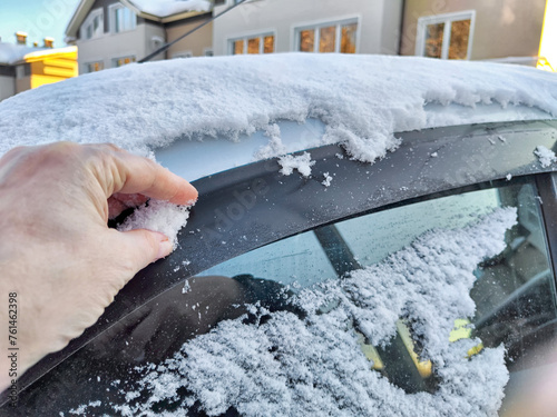 Hand of Woman persons brushing snow of a car window, which frozen over during a bitterly cold morning. Problem with travel and trip in winter