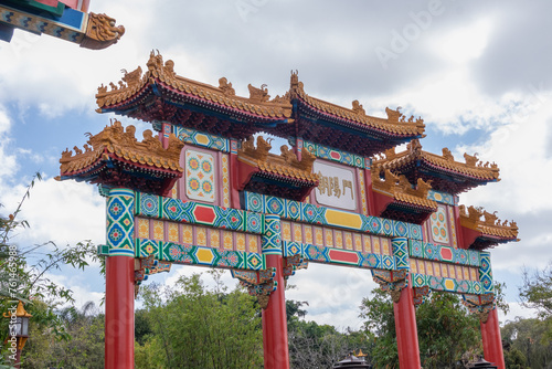 Chinese temple wall with carved figures and arches with cloudy sky