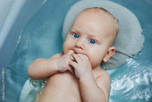 Hygiene of newborns and children. The baby lies on a stand and bathes in a bathtub. Bathing a newborn baby in a bath